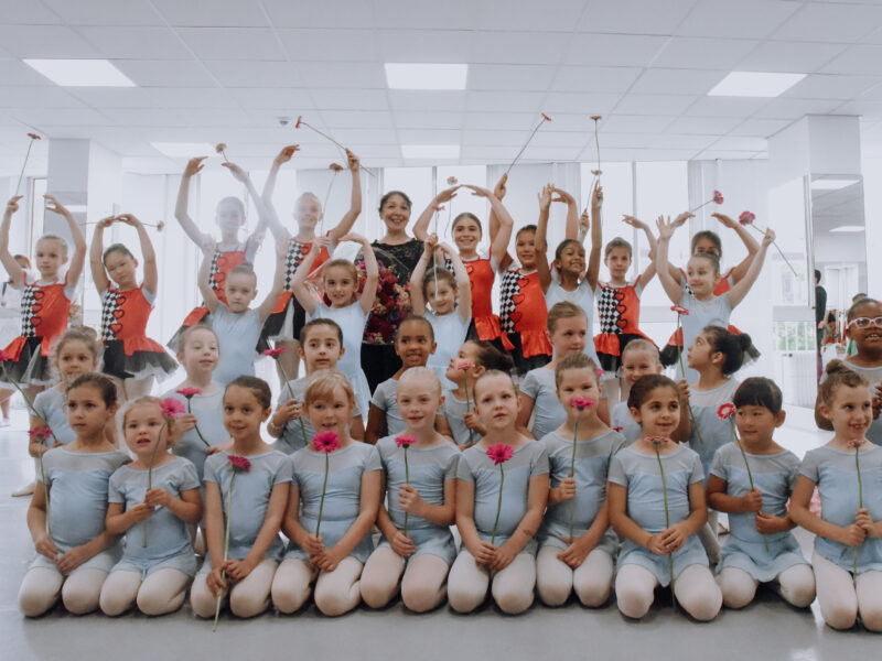 children in a ballet studio holding flowers after the show