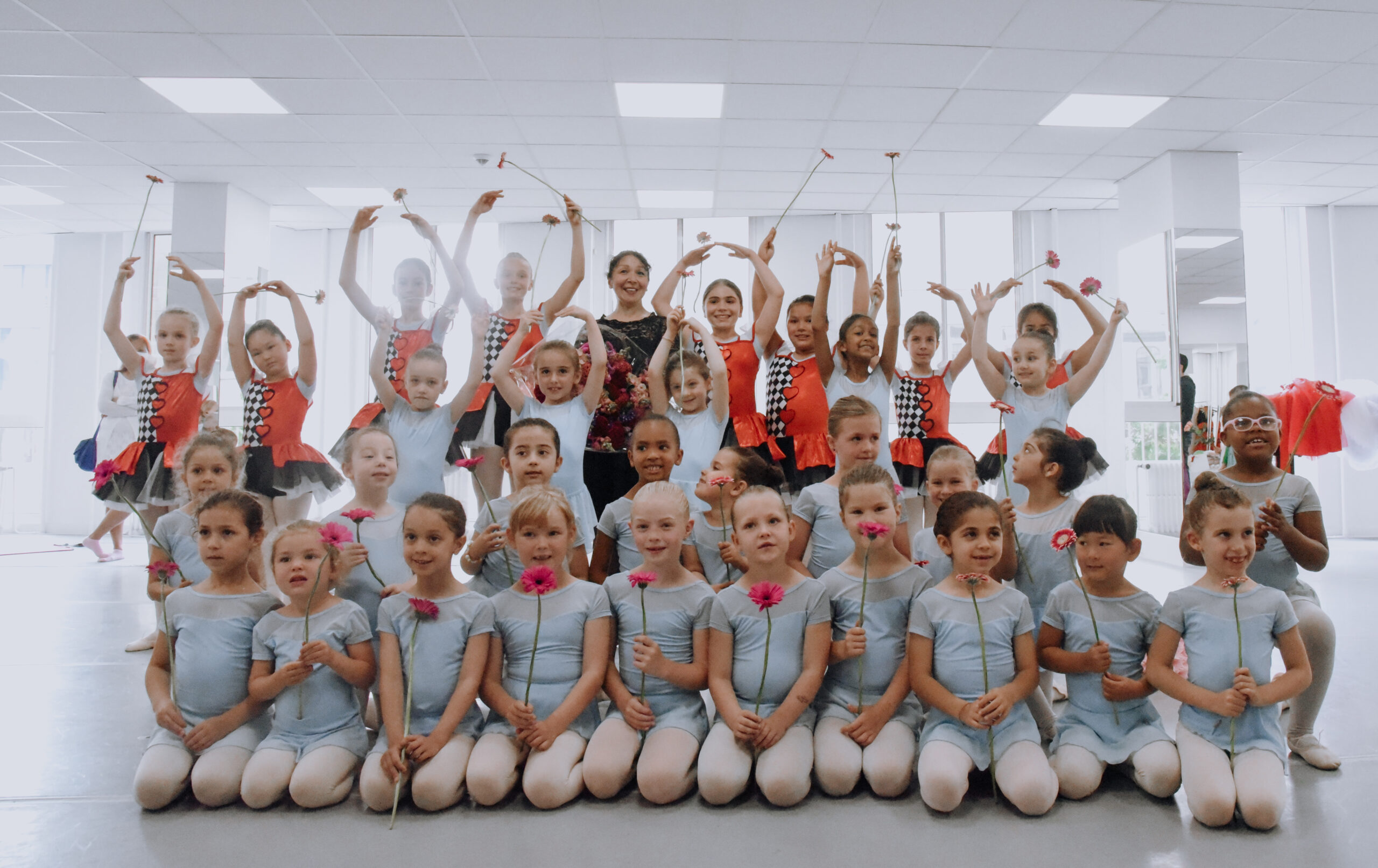 children in a ballet studio holding flowers after the show